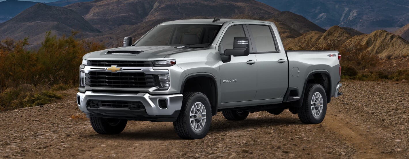 Side view of the 2026 Silverado 2500 HD LT in Sterling Gray Metallic on a gravel road.