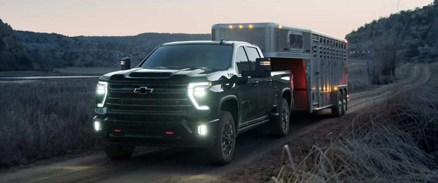 Front view of a Silverado 2500 HD LTZ Trail Boss in Black towing a horse trailer.