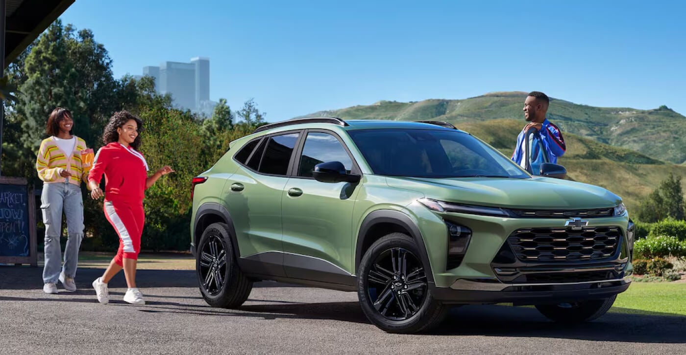 Friends surrounding 2026 Chevy Trax with joyous expressions.
