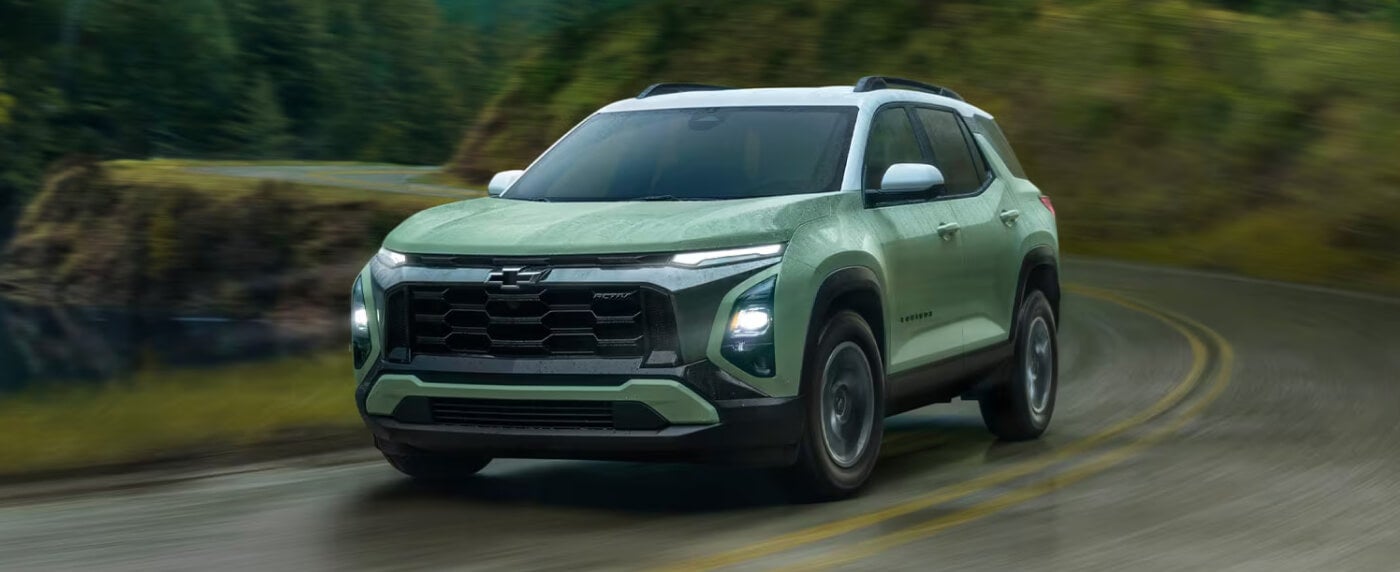 2026 Chevy Equinox EV in Green Driving Down a Winding Road