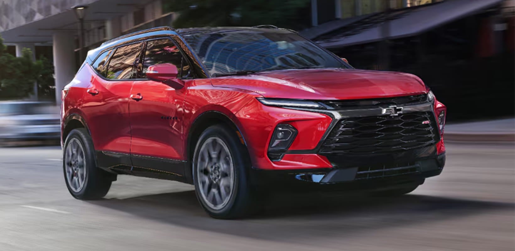 Red Chevrolet Blazer RS driving through a city street.