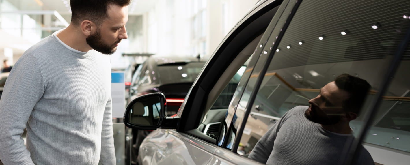 Customer examining a vehicle inside a dealership showroom.